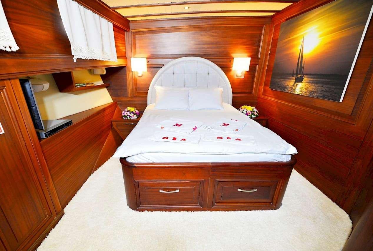 a bed with a white sheet and a wooden headboard aboard MIA 1 Yacht for Charter