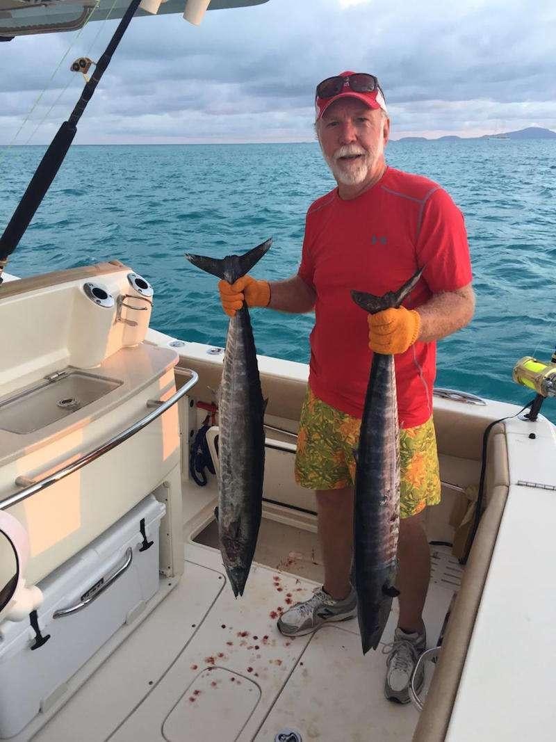 a man holding a fish aboard MIDNIGHT MOON Yacht for Charter