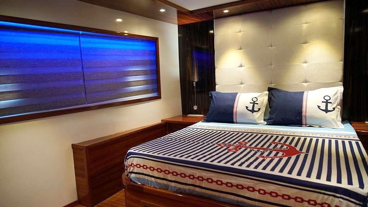a bed with a blue and white striped bed spread aboard SADIYE HANIM Yacht for Charter