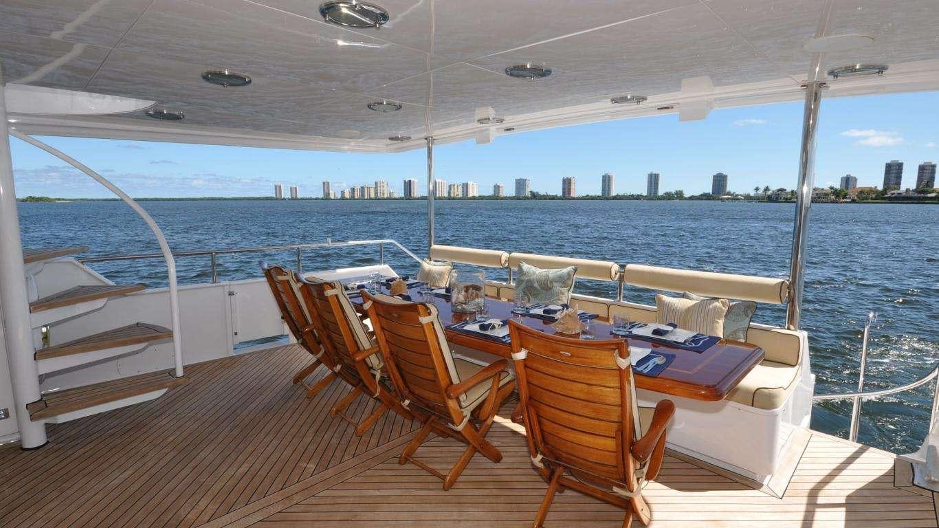 a deck with chairs and tables on it by a large body of water aboard LUCKY STARS Yacht for Charter