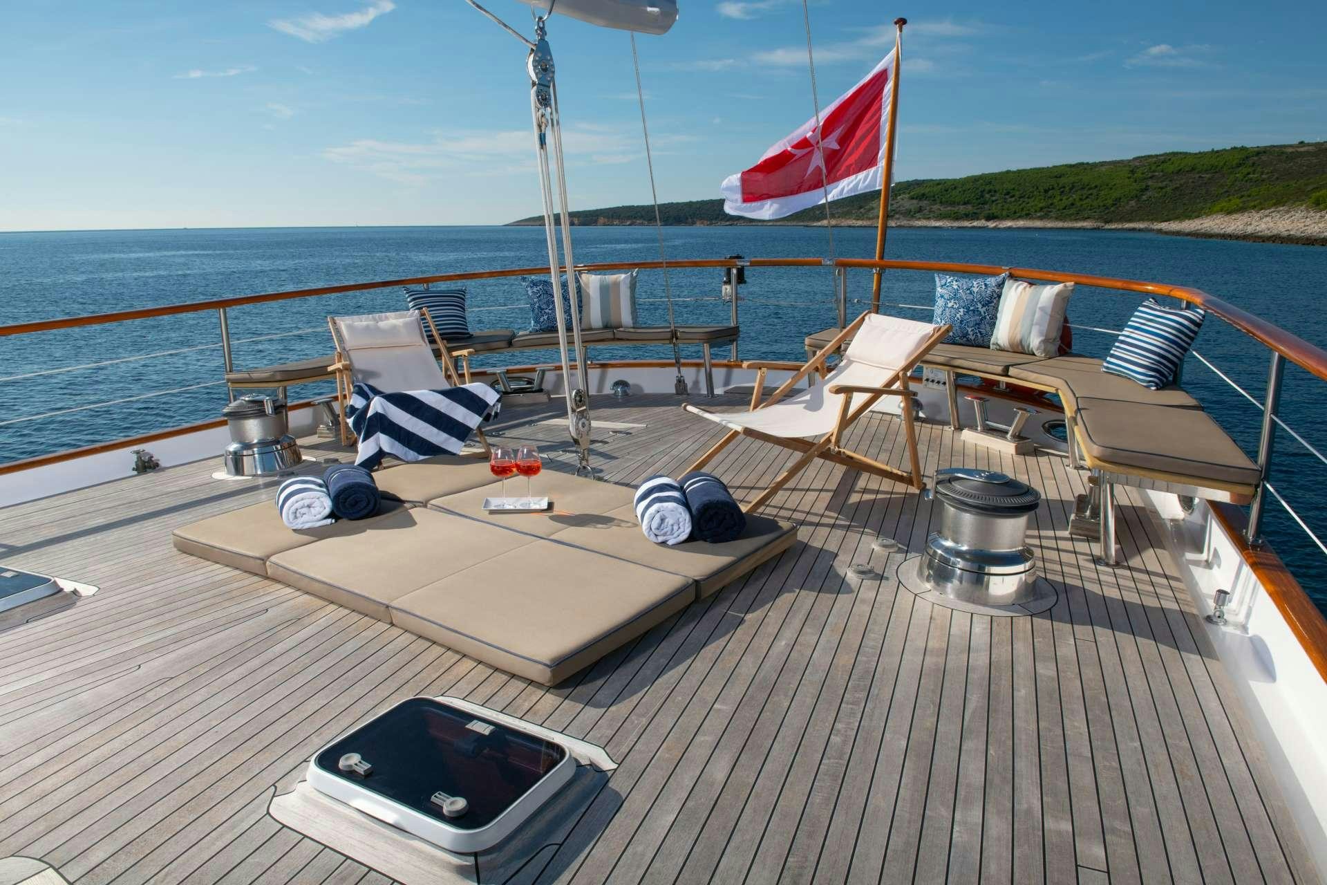 a deck with chairs and a boat on it aboard Free Wings Yacht for Charter