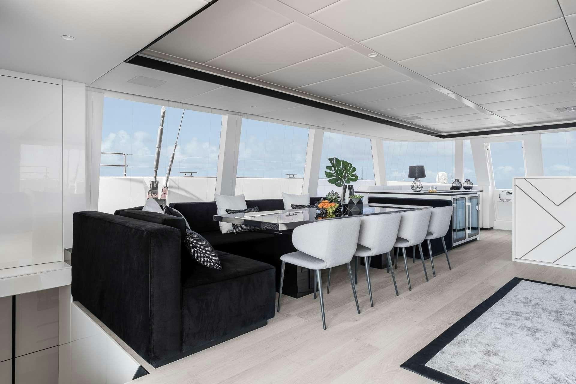 a black couch in a room with white chairs and a table aboard ABOVE AND BEYOND Yacht for Charter