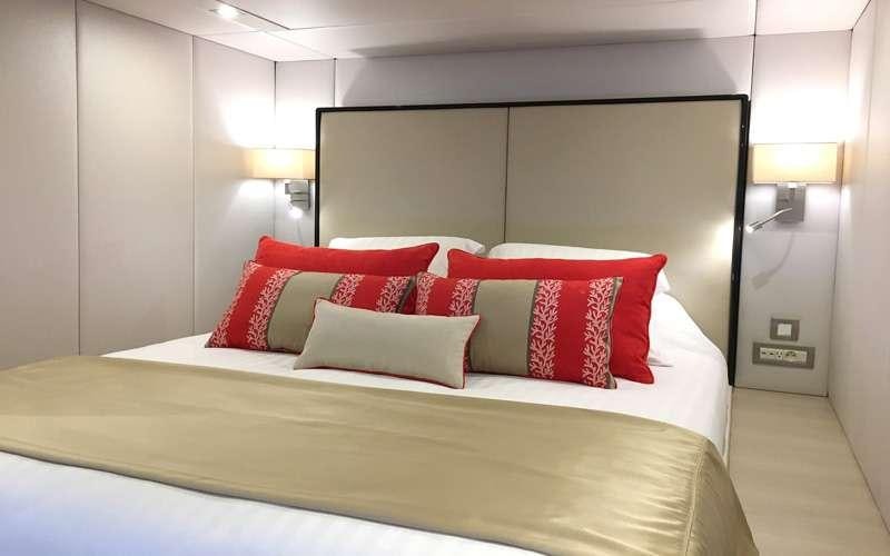 a bed with red pillows aboard MAYRILOU Yacht for Charter