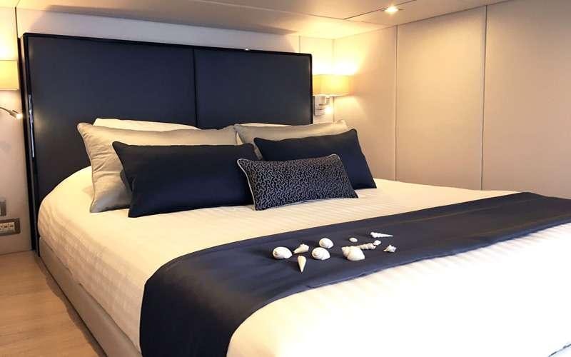 a bed with a black bed spread aboard MAYRILOU Yacht for Charter