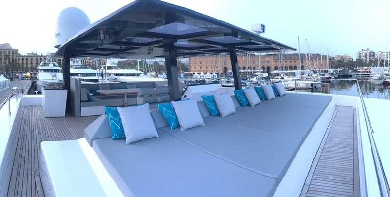 a large lounge area with a large patio and a large building with a city in the background aboard MAYRILOU Yacht for Charter