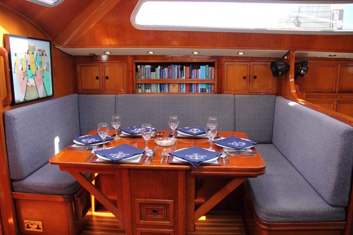 a table with wine glasses and a couch in a room with wood cabinets aboard EMILY MORGAN Yacht for Charter