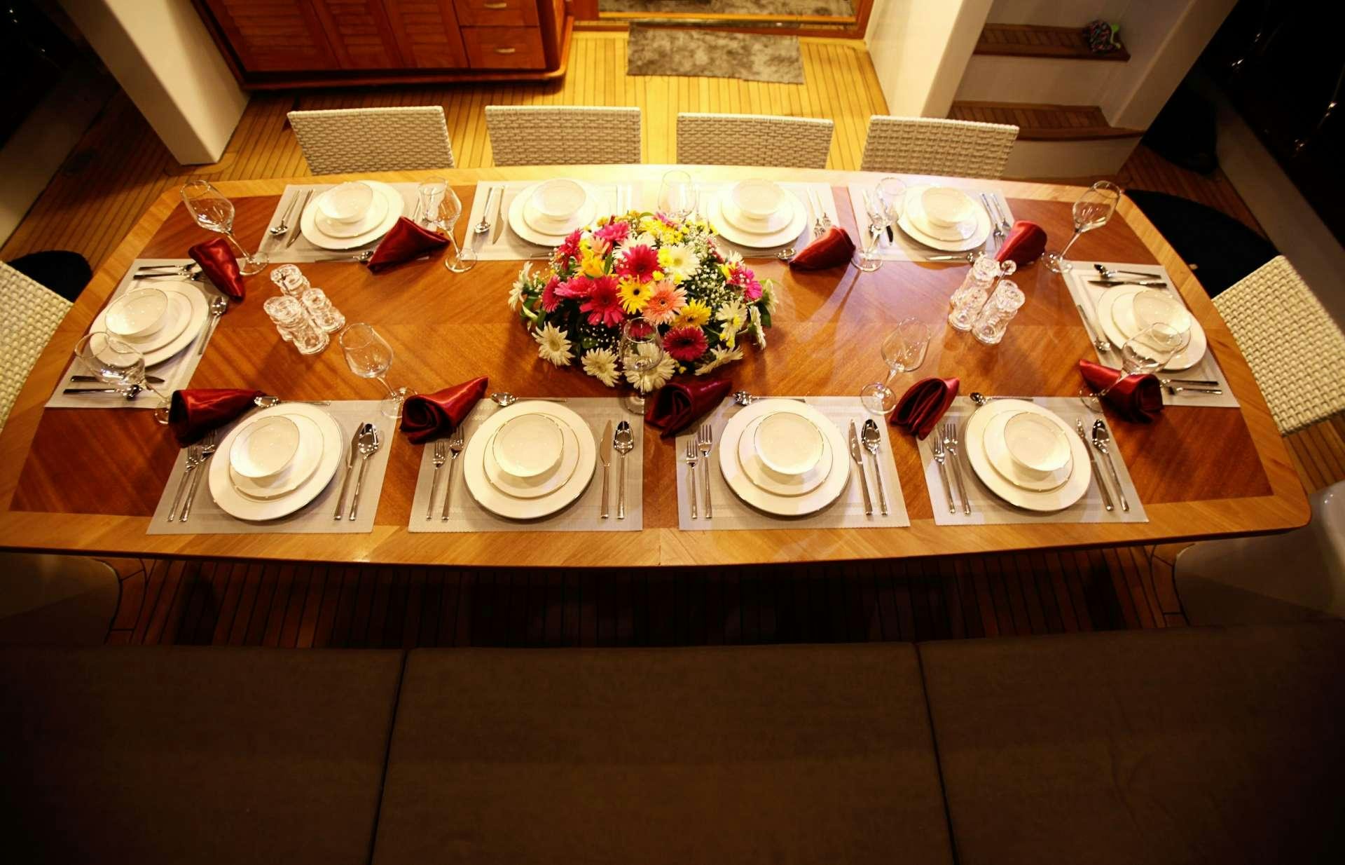 a table set with plates and flowers aboard CROCUS Yacht for Charter