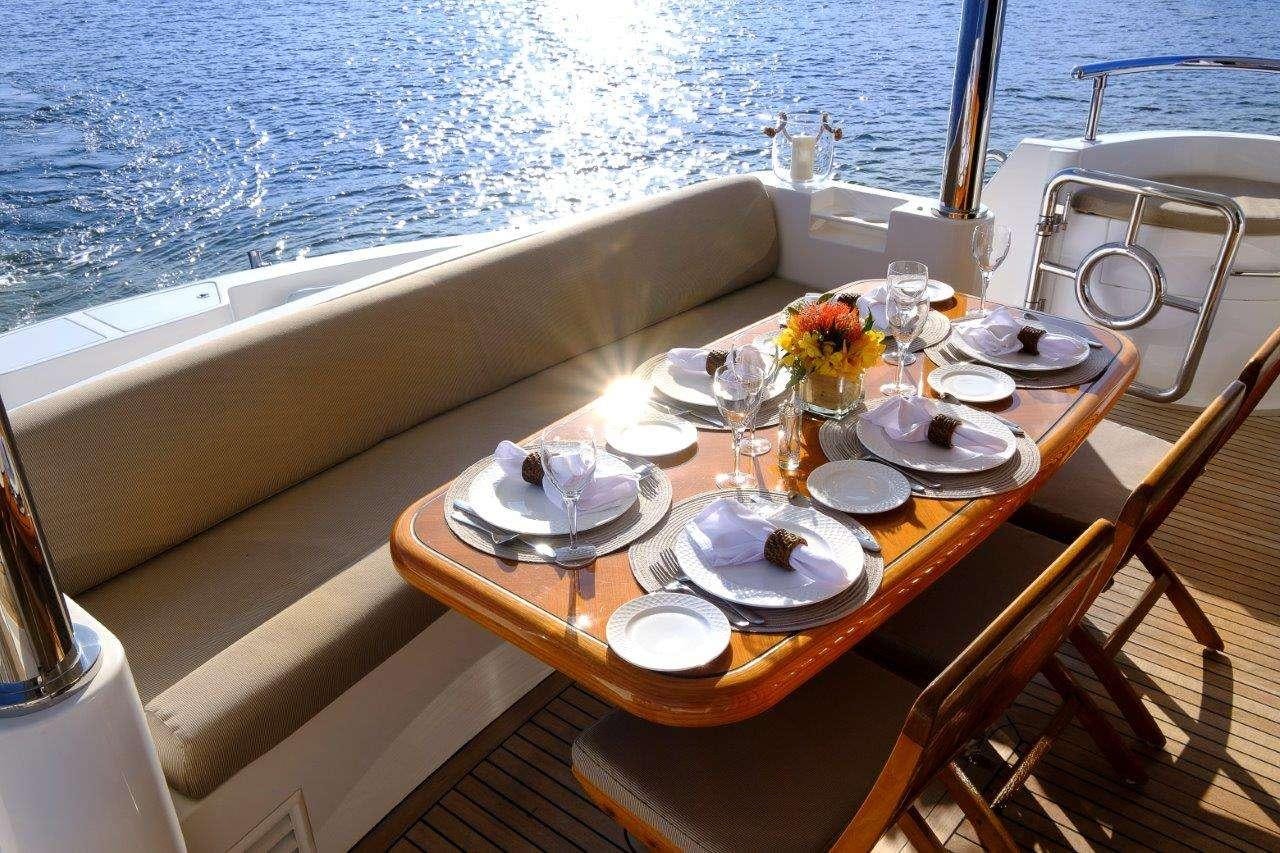 a table with plates and glasses on it next to a body of water aboard SILVER LINING Yacht for Charter