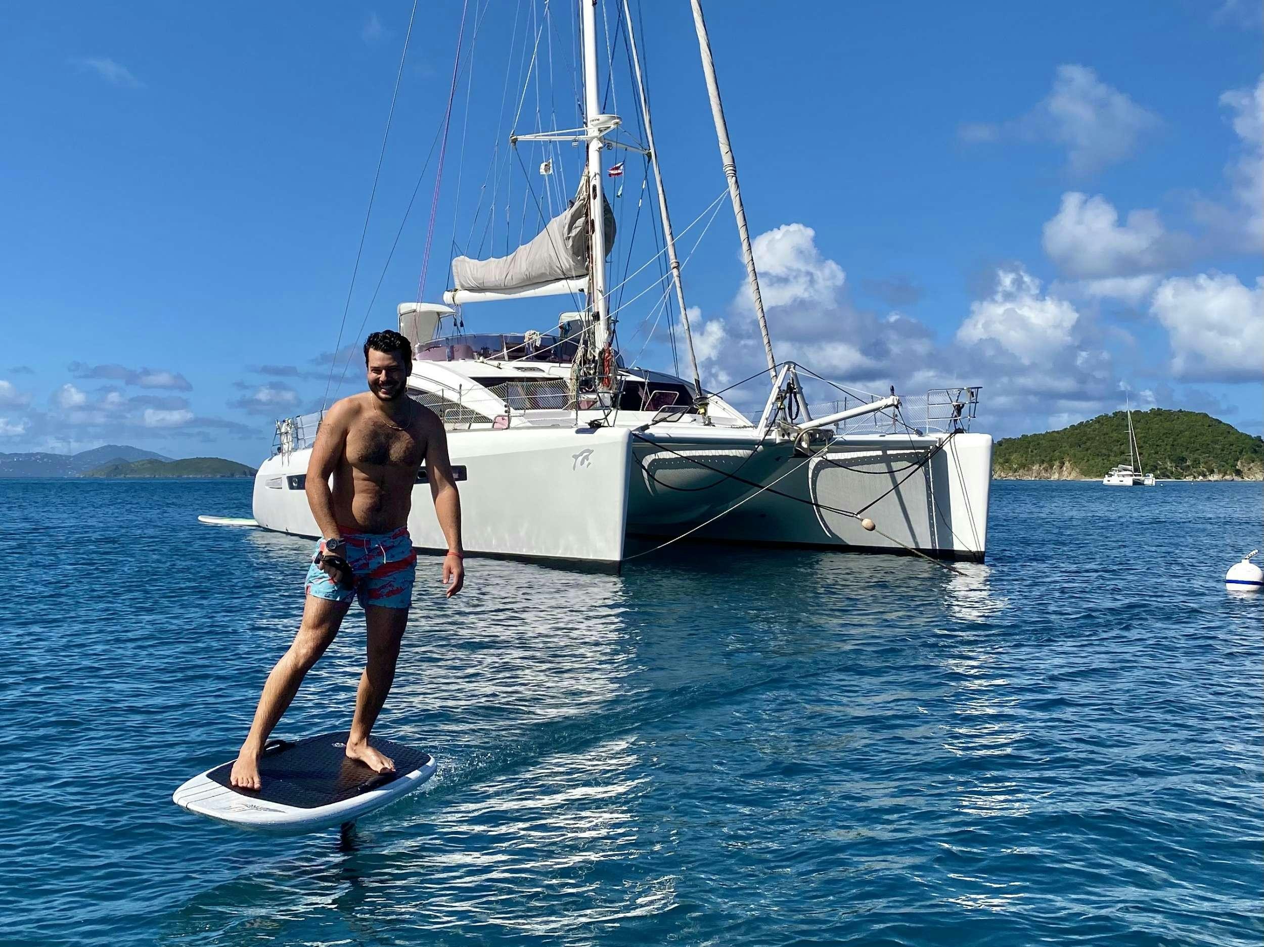 a man on a surfboard in front of a sailboat aboard TRES SUENOS Yacht for Charter