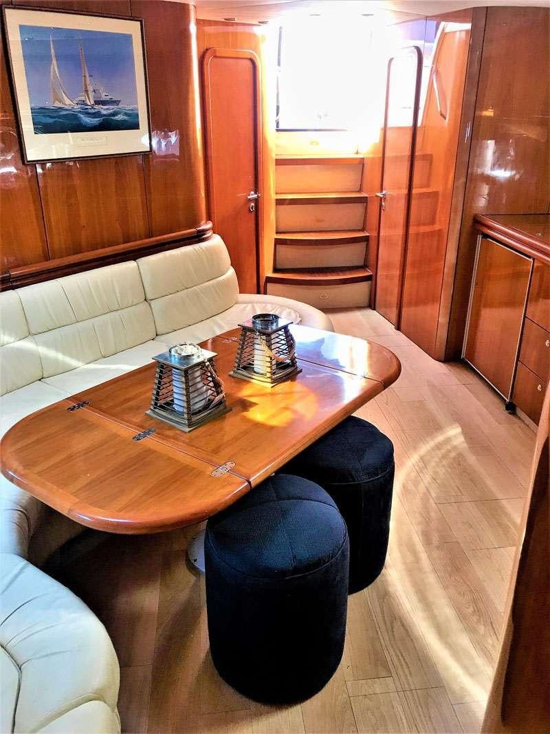 a table with a couch and a chair in a room with wood walls aboard OBSESSION Yacht for Charter