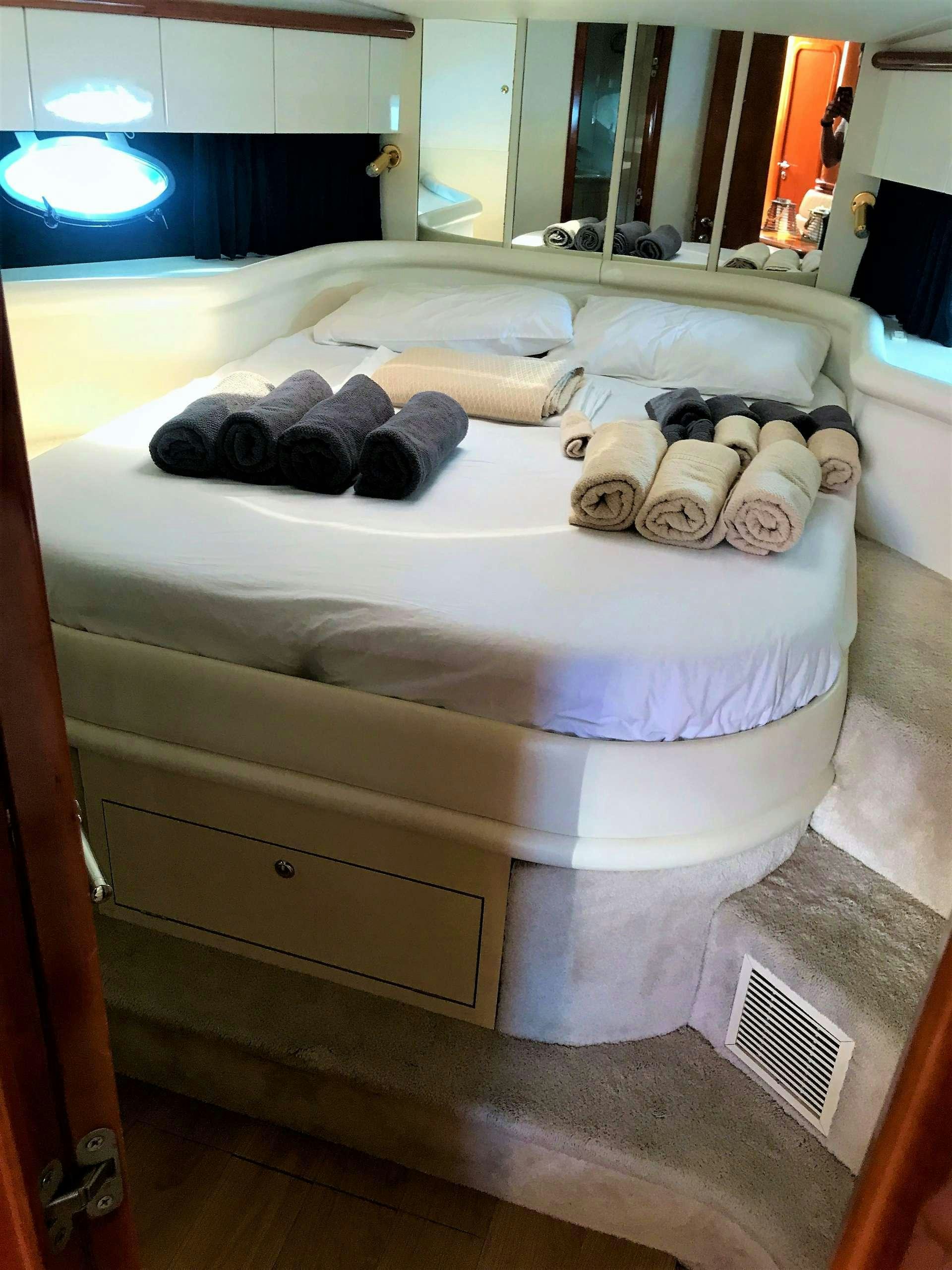 a bed with white sheets and pillows aboard OBSESSION Yacht for Charter
