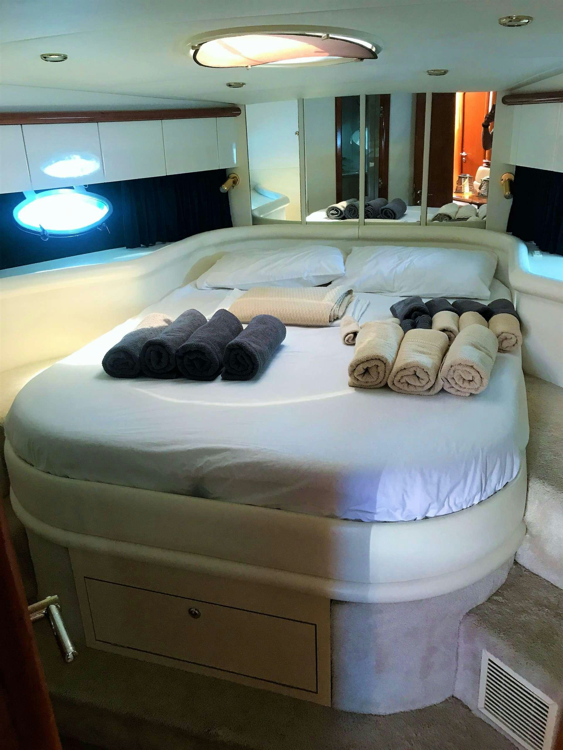 a bed with white sheets and pillows aboard OBSESSION Yacht for Charter