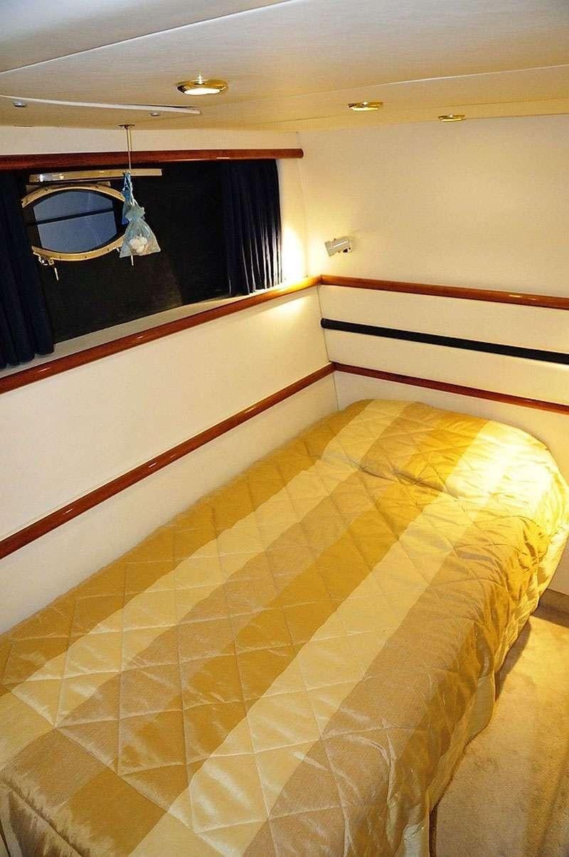 a bed with a yellow blanket aboard OBSESSION Yacht for Charter