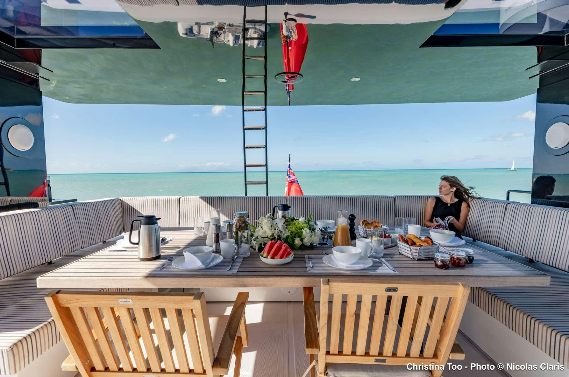 a person sitting at a table with food on it aboard CHRISTINA TOO Yacht for Charter