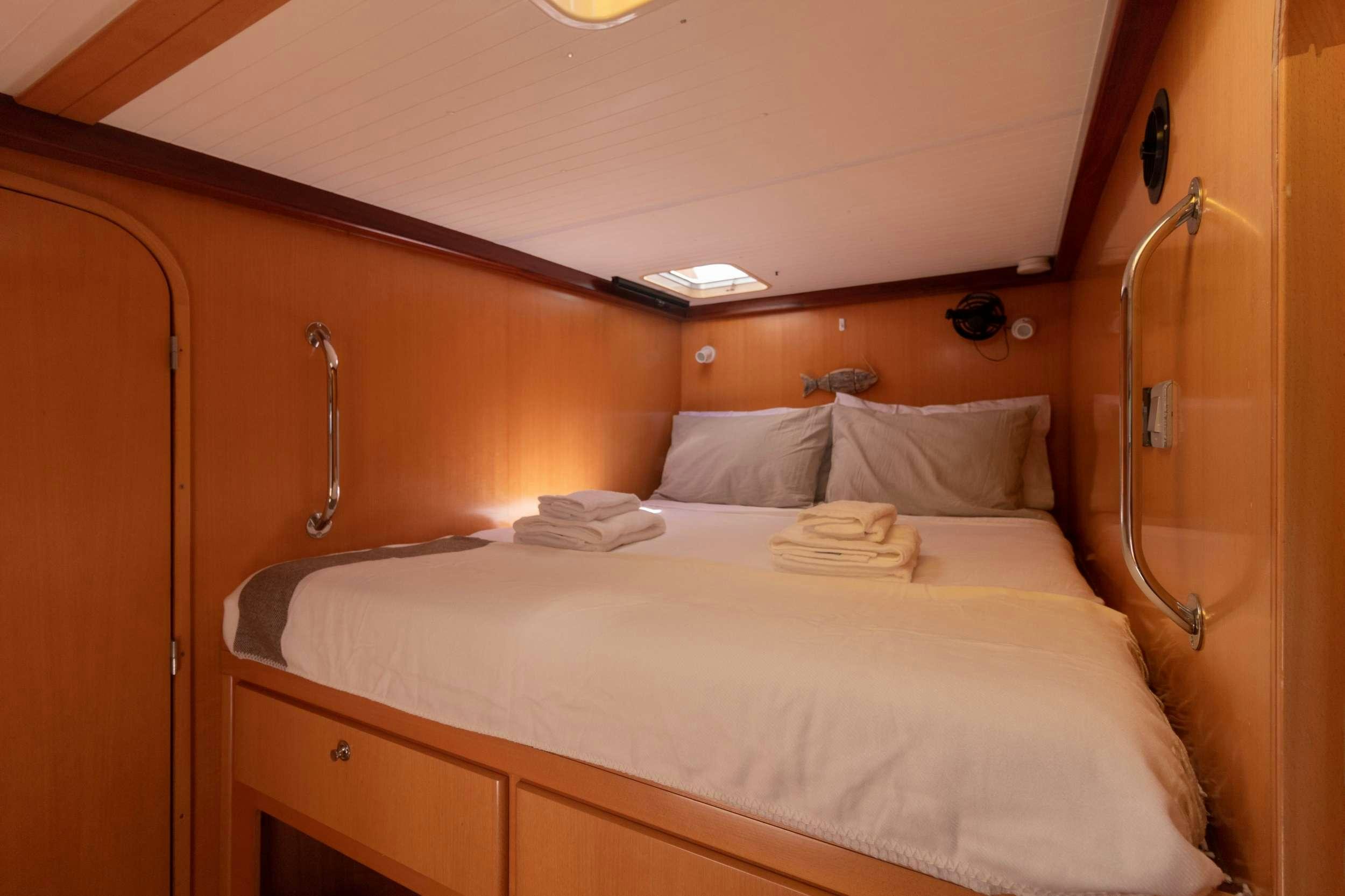a bed with white sheets aboard NEMO Yacht for Charter