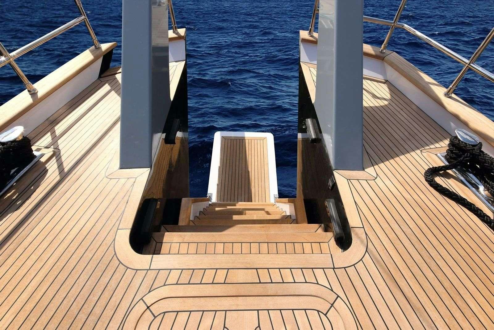 a deck with a railing and a railing with a body of water in the background aboard MOSS Yacht for Charter