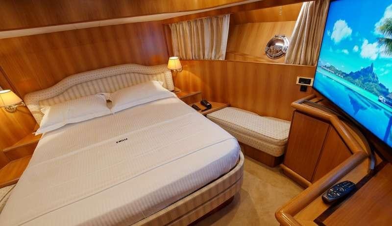a room with a bed and a television aboard EMILIA Yacht for Charter