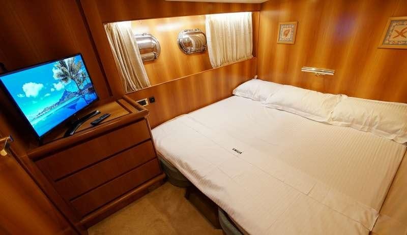 a room with a bed and a television aboard EMILIA Yacht for Charter