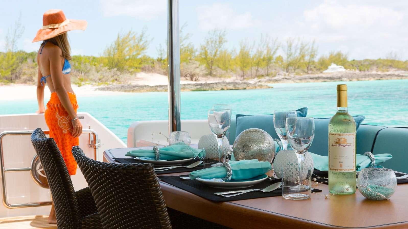 a person in a bikini on a table with wine glasses and a bottle of wine aboard MYSTIC SOUL Yacht for Charter
