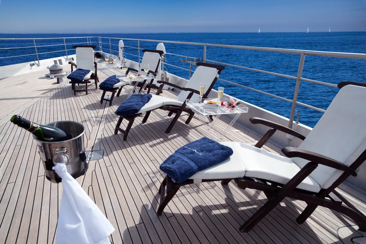 a deck with chairs and a table on it aboard DWINGER Yacht for Charter