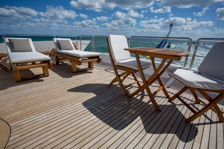 a deck with chairs and a table on it aboard HAPPY HOUR Yacht for Charter