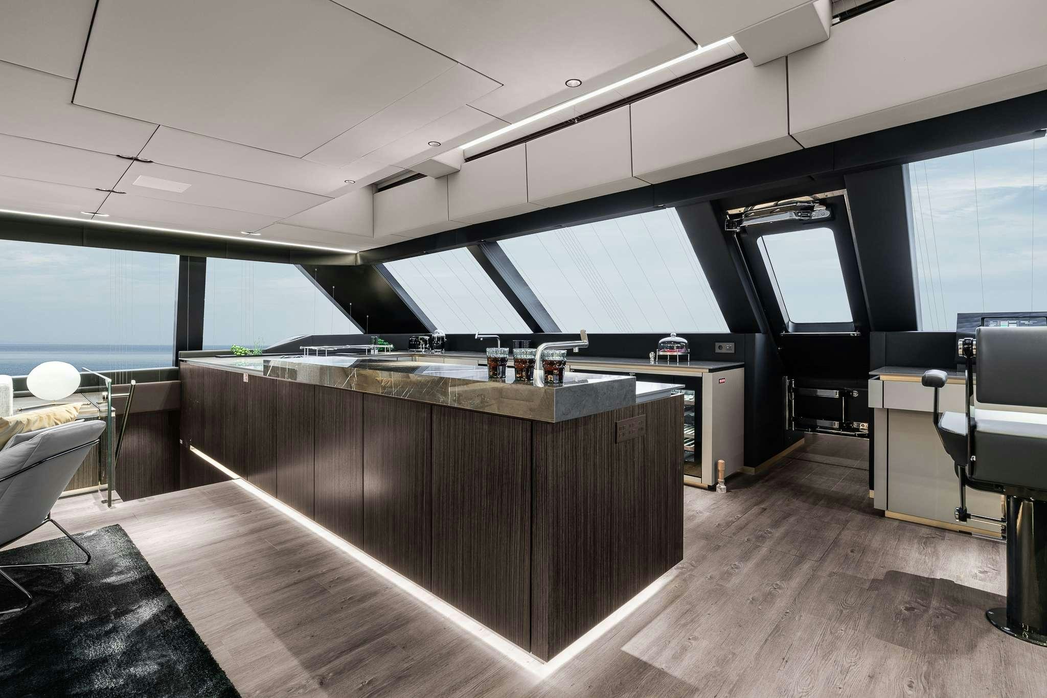 a room with a large window and a wood table with a view of the ocean aboard SEIYA Yacht for Charter