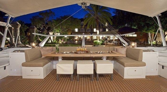 a large room with a table and chairs and a large pool aboard MAGIC CAT Yacht for Charter