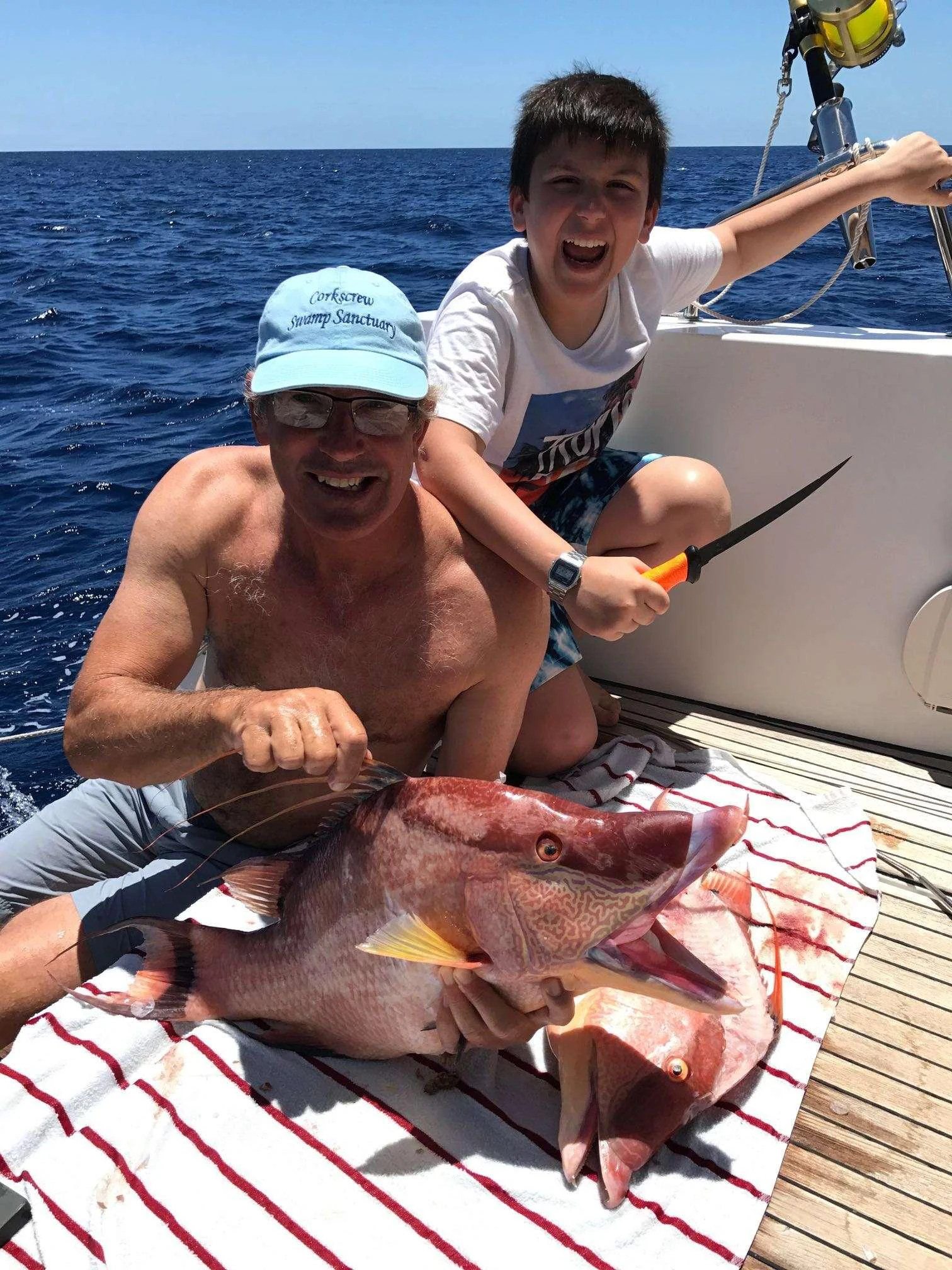 a man holding a fish next to a man in a boat aboard Samoru ll Yacht for Charter