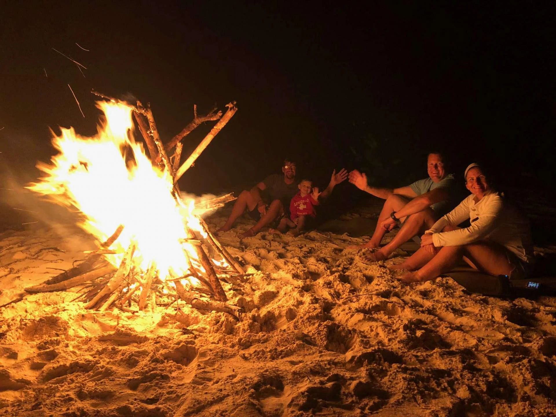 a group of people sitting around a campfire aboard Samoru ll Yacht for Charter
