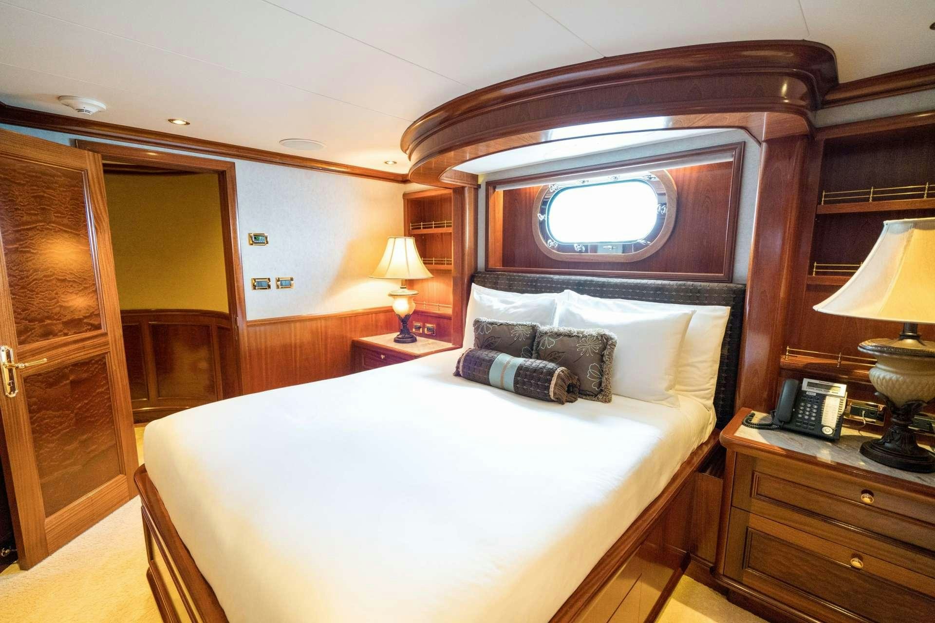 a bed with a white sheet and pillows in a room with a wood door and a mirror aboard EXCELLENCE Yacht for Charter