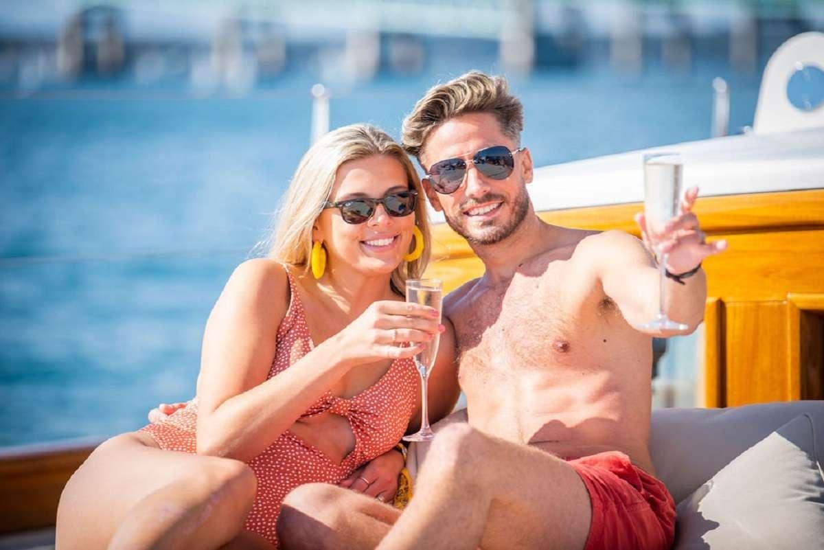 a man and woman holding glasses of wine and smiling at the camera aboard AURELIUS 111 Yacht for Charter