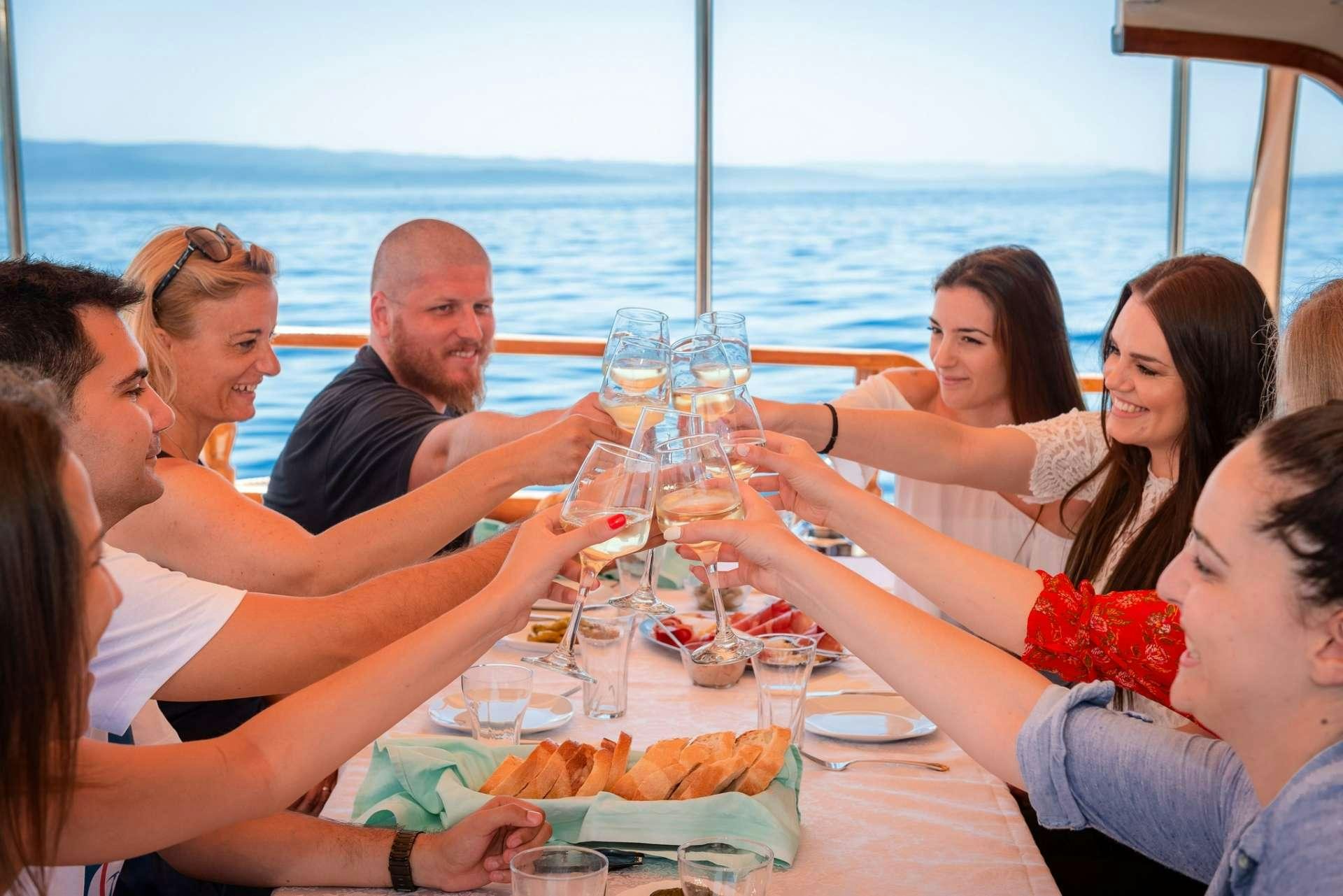 a group of people sitting at a table with food and drinks aboard Dona Yacht for Charter