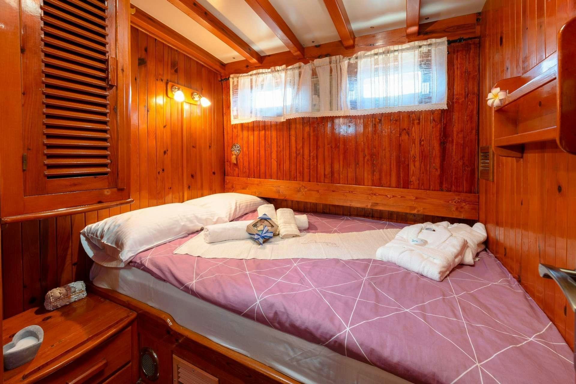 a bed with a pink comforter aboard Dona Yacht for Charter
