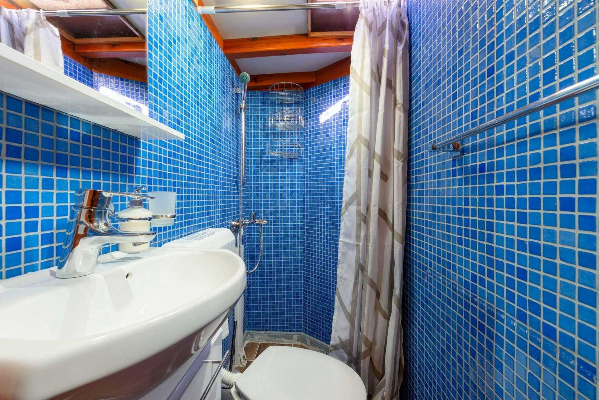 a bathroom with blue tiles aboard Dona Yacht for Charter