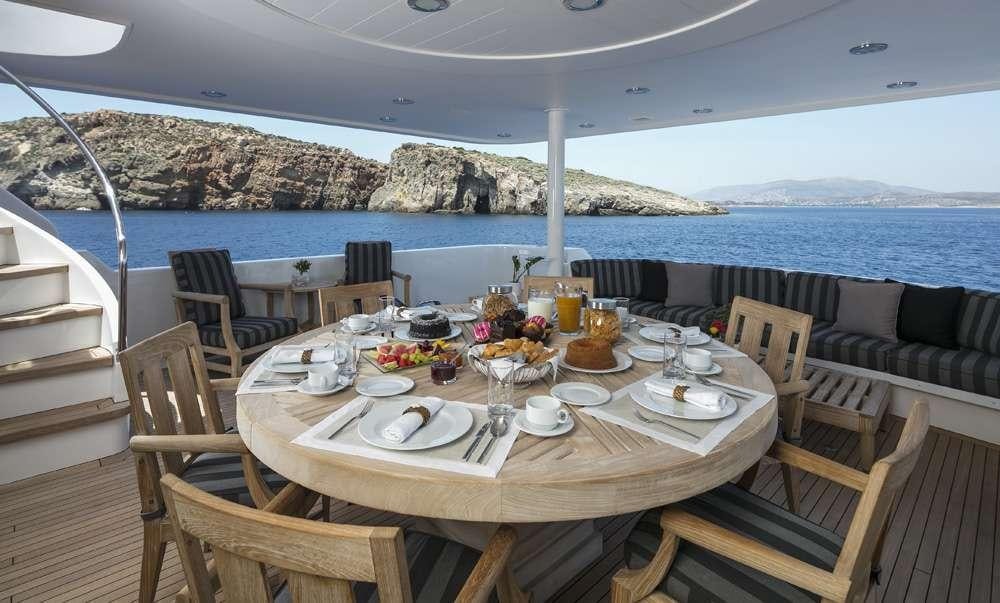 a table set for a meal on a balcony overlooking a large body of water aboard ENDLESS SUMMER Yacht for Charter