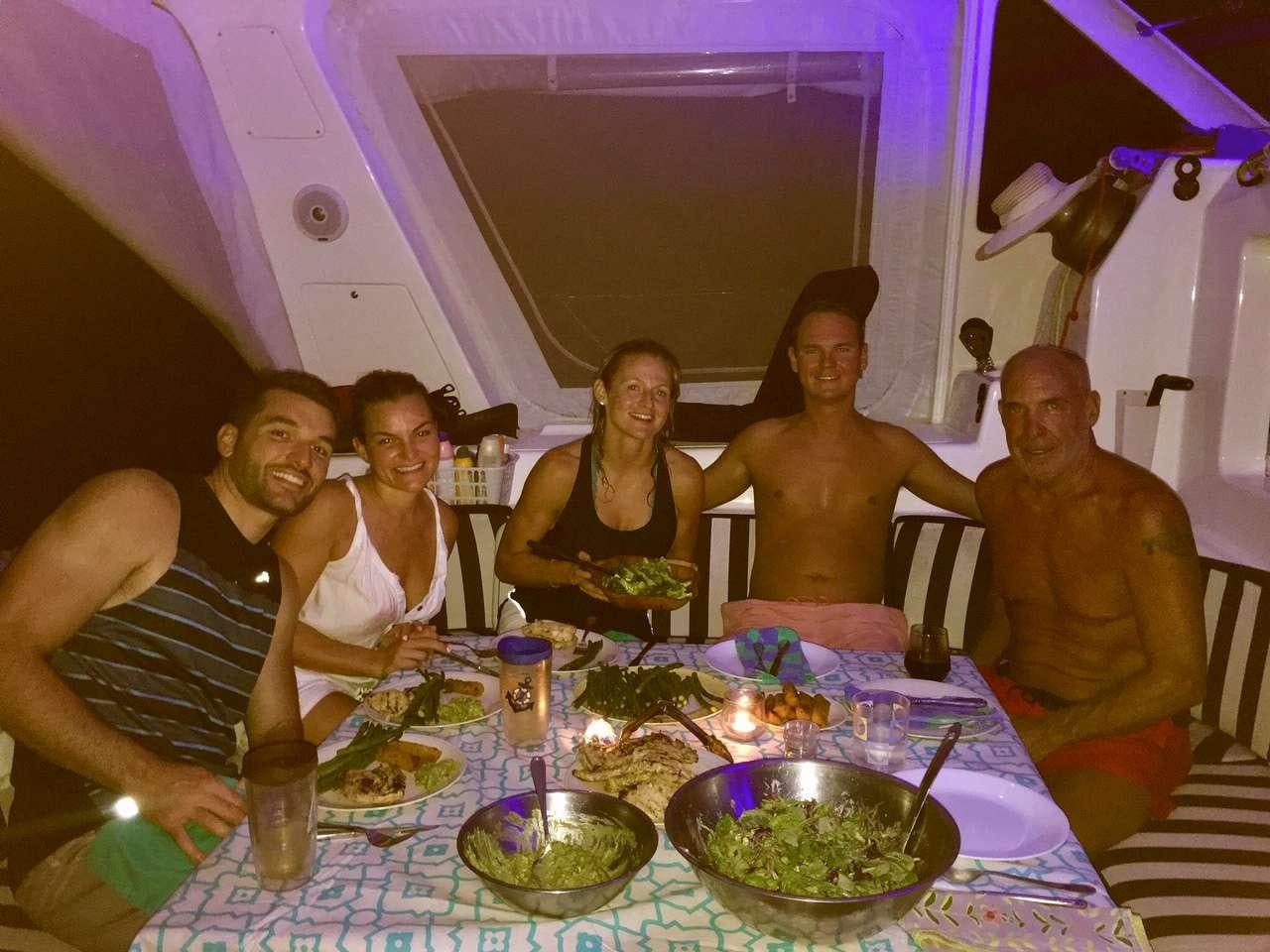 a group of people sitting around a table with food aboard GUINEVERE Yacht for Charter