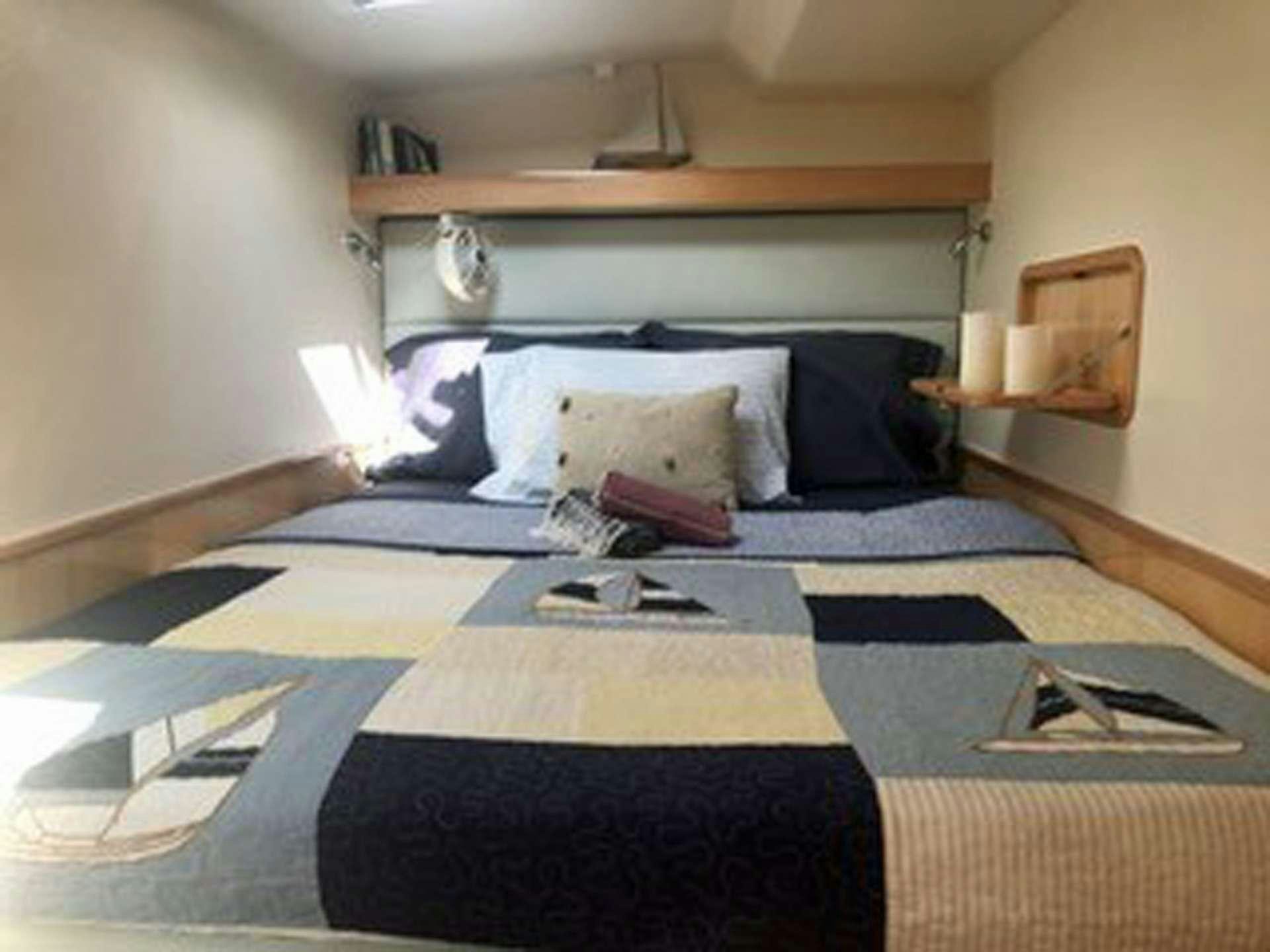 a bed with a blue comforter aboard GUINEVERE Yacht for Charter