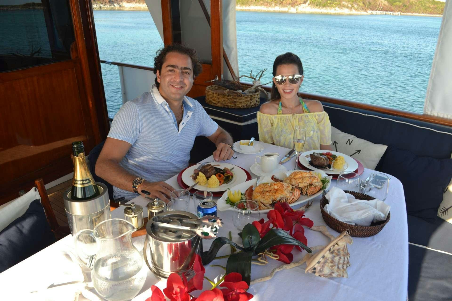 a man and woman sitting at a table with food on it aboard BONAPARTE Yacht for Charter