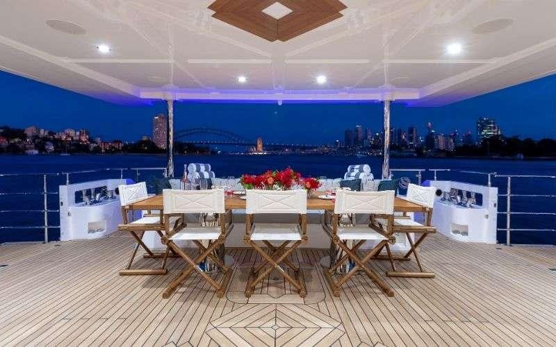 a room with tables and chairs aboard ONEWORLD Yacht for Charter