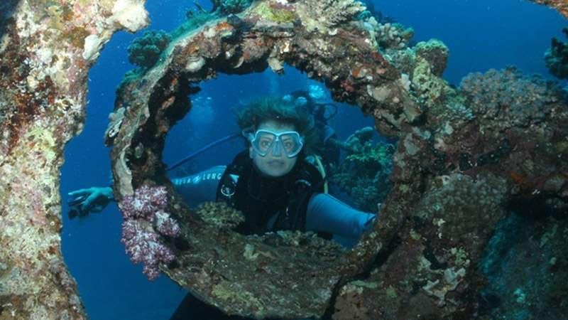 a person in scuba gear under a rock formation aboard SASHA Yacht for Charter