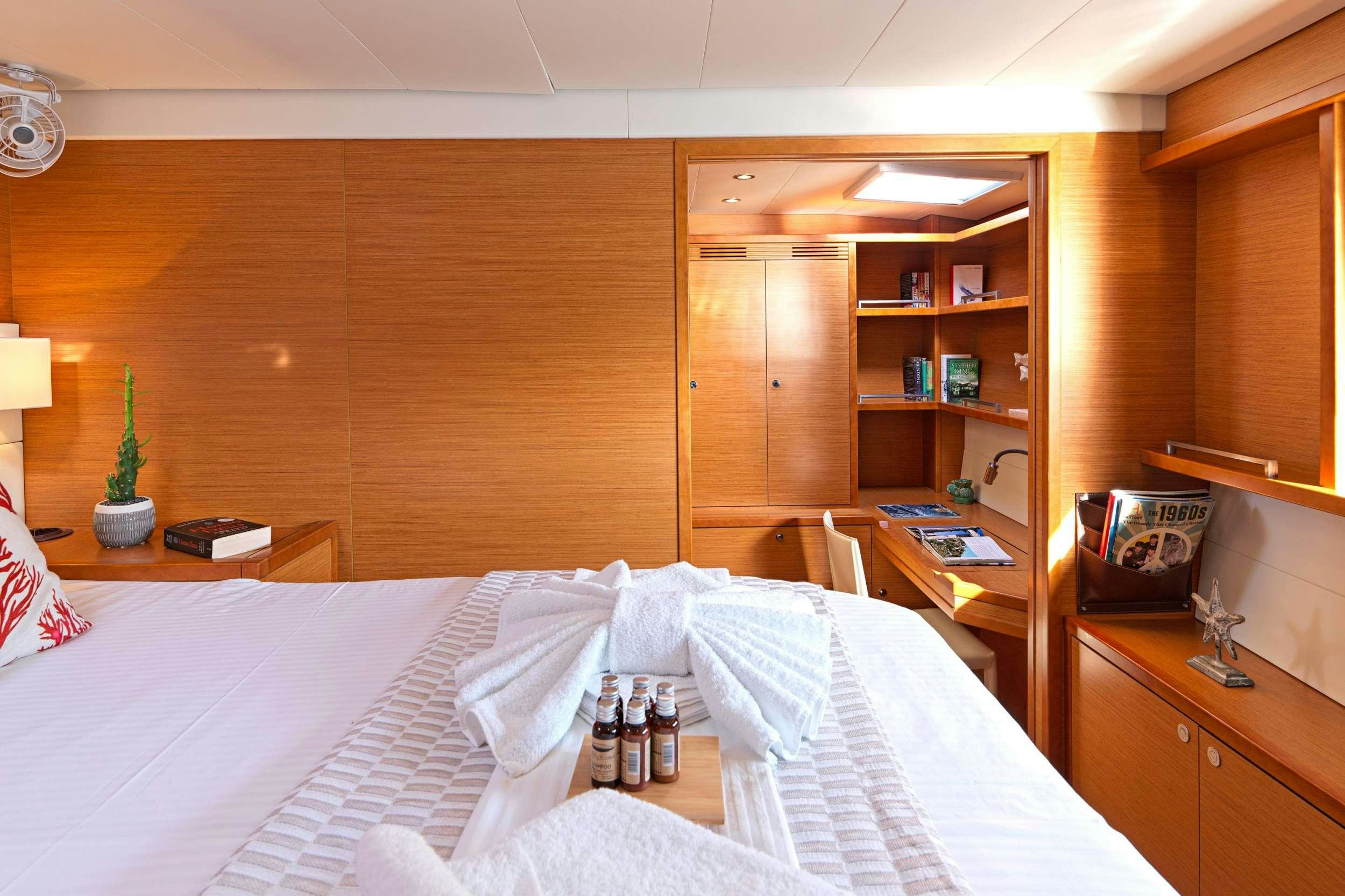 a room with a bed and a shelf with wine bottles aboard GOLDEN PEARL Yacht for Charter