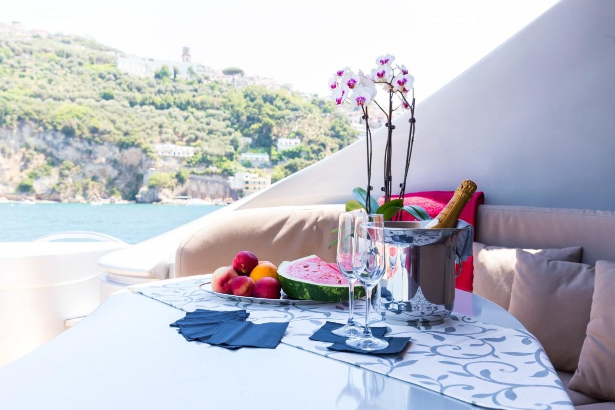 a table with a vase of flowers and a glass of wine aboard CINQUE Yacht for Charter