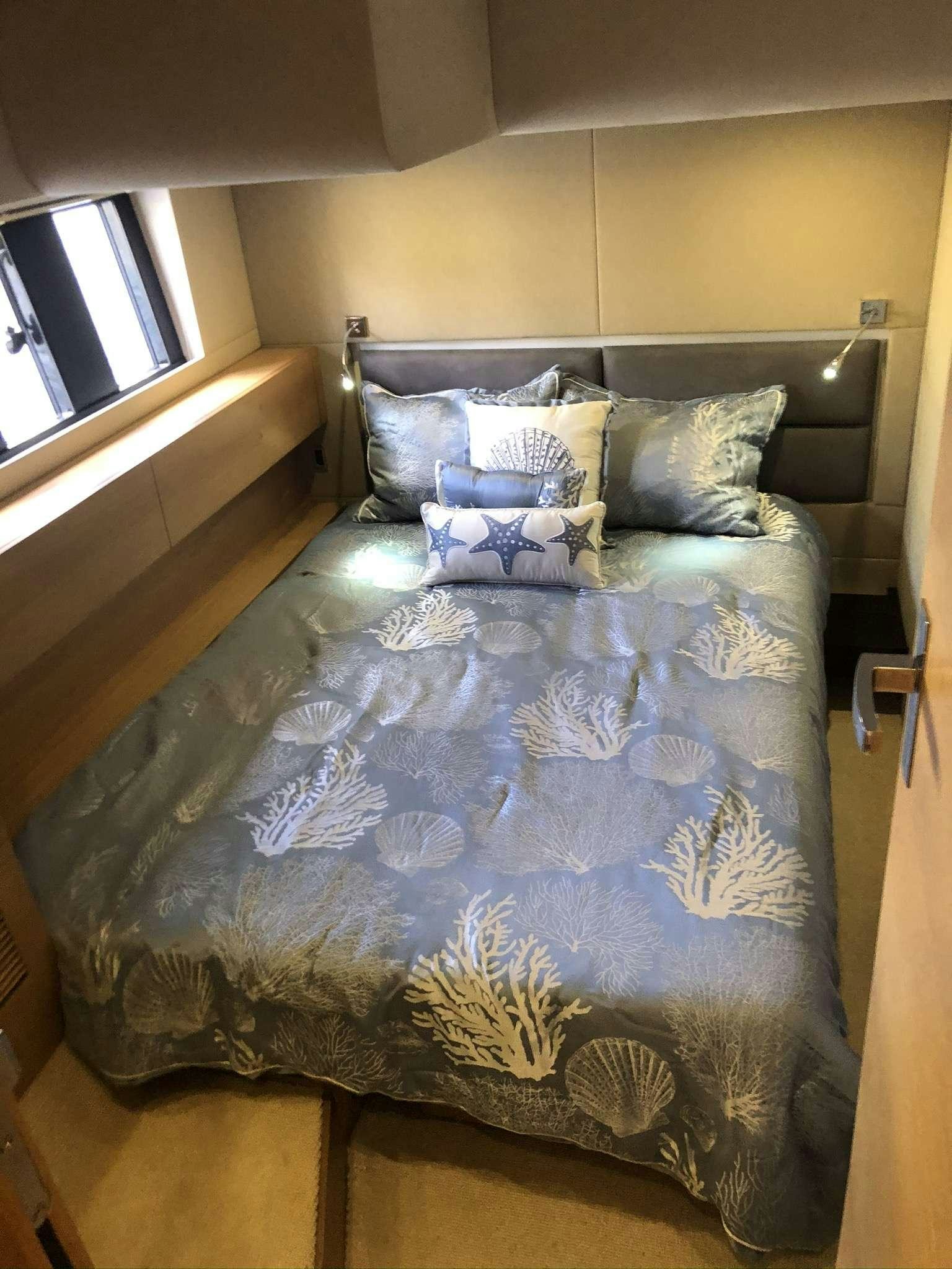 a bed with blue sheets aboard Synergy Yacht for Charter
