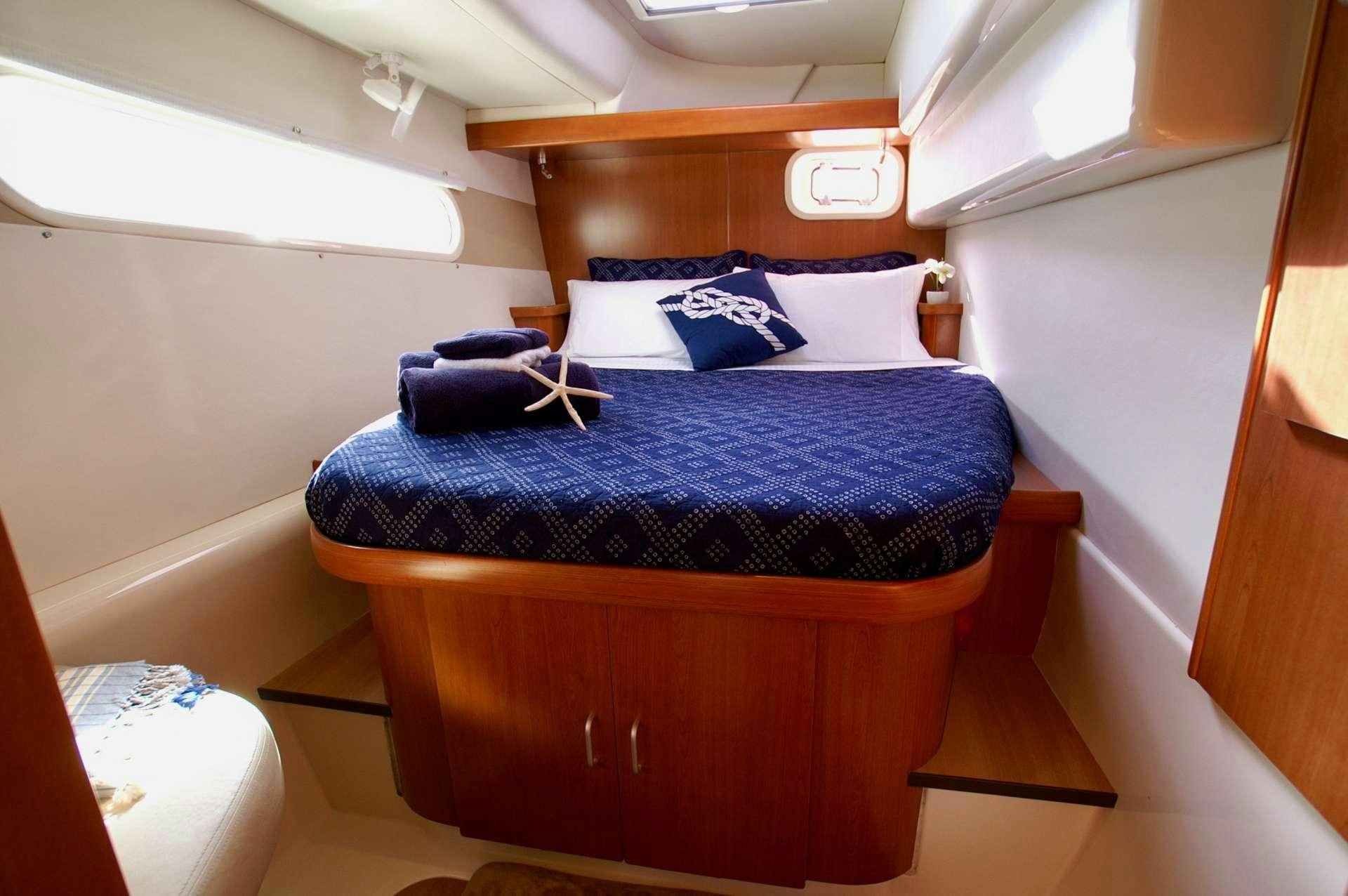 a bed with blue sheets aboard EXTASEA 2 Yacht for Charter