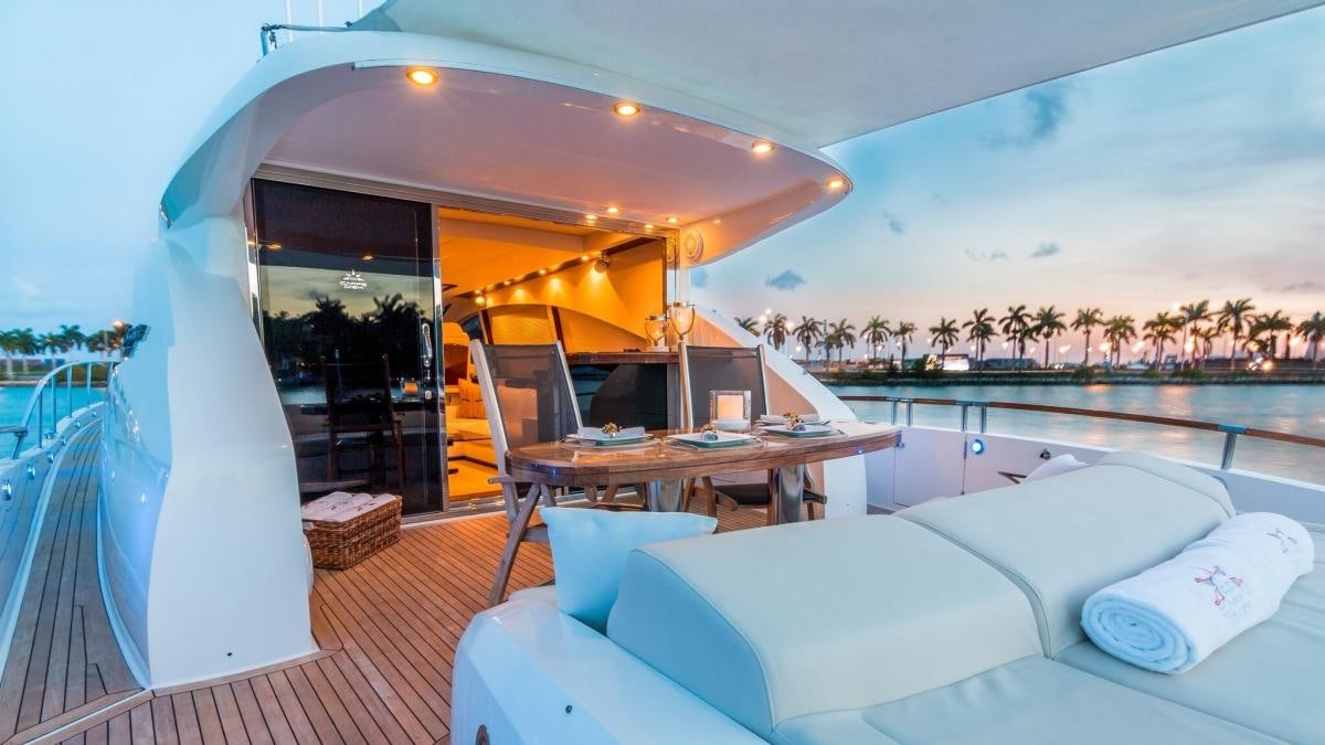 a lounge area with a table and chairs on a deck with a view of the water and trees aboard CARPE DIEM Yacht for Charter