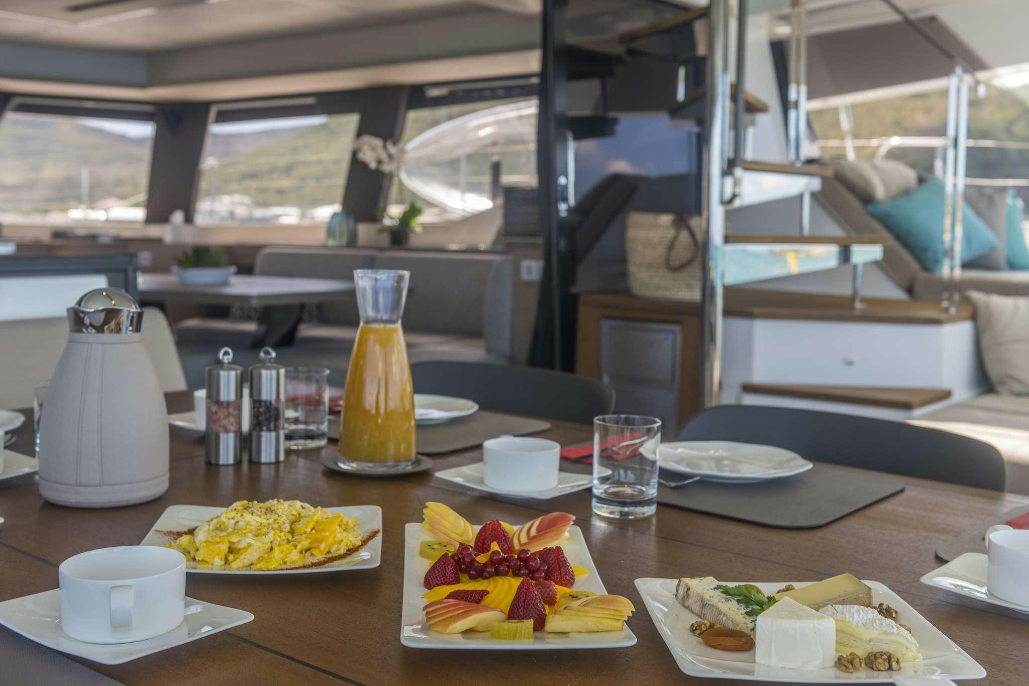 a table with plates of food and cups on it aboard LISA OF THE SEAS Yacht for Charter