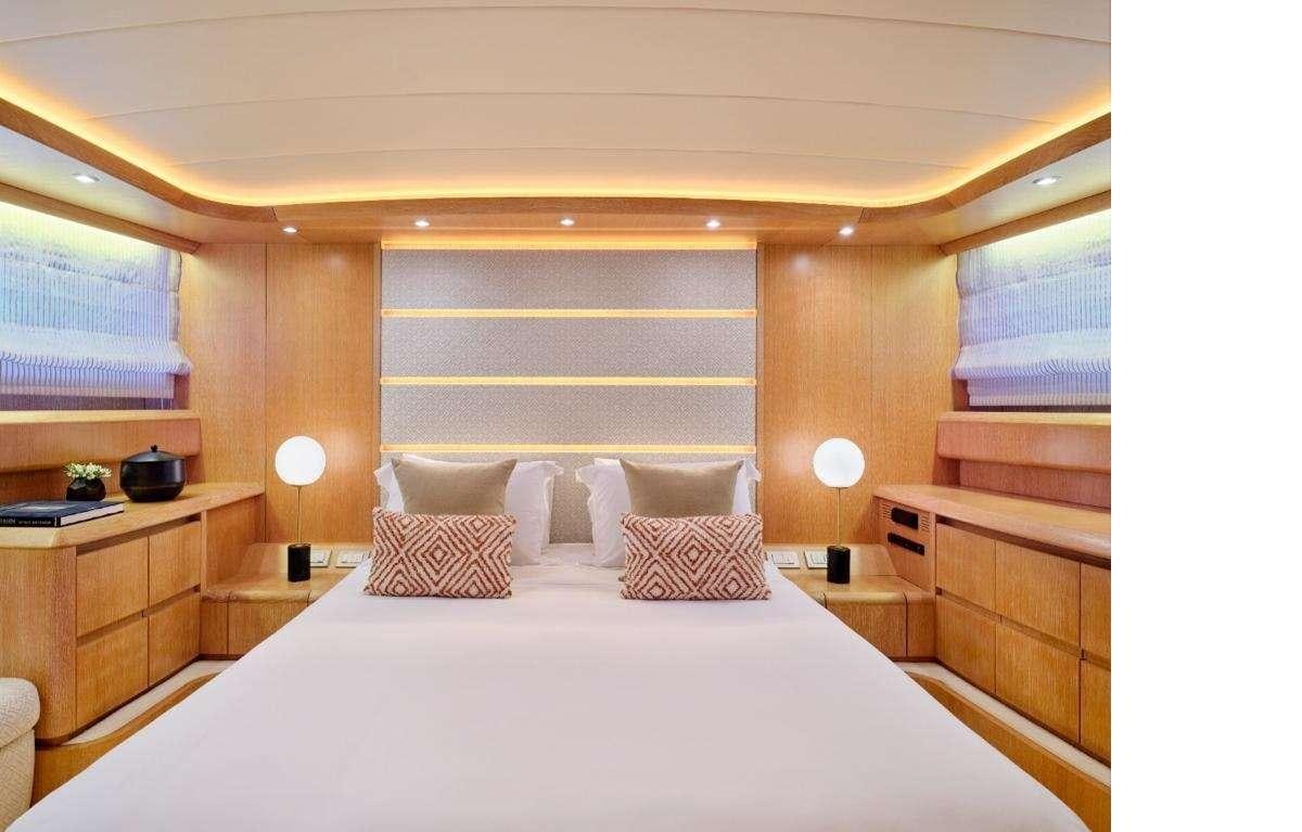 a bed with a white sheet and pillows in a room with wood cabinets aboard IRENE'S Yacht for Charter