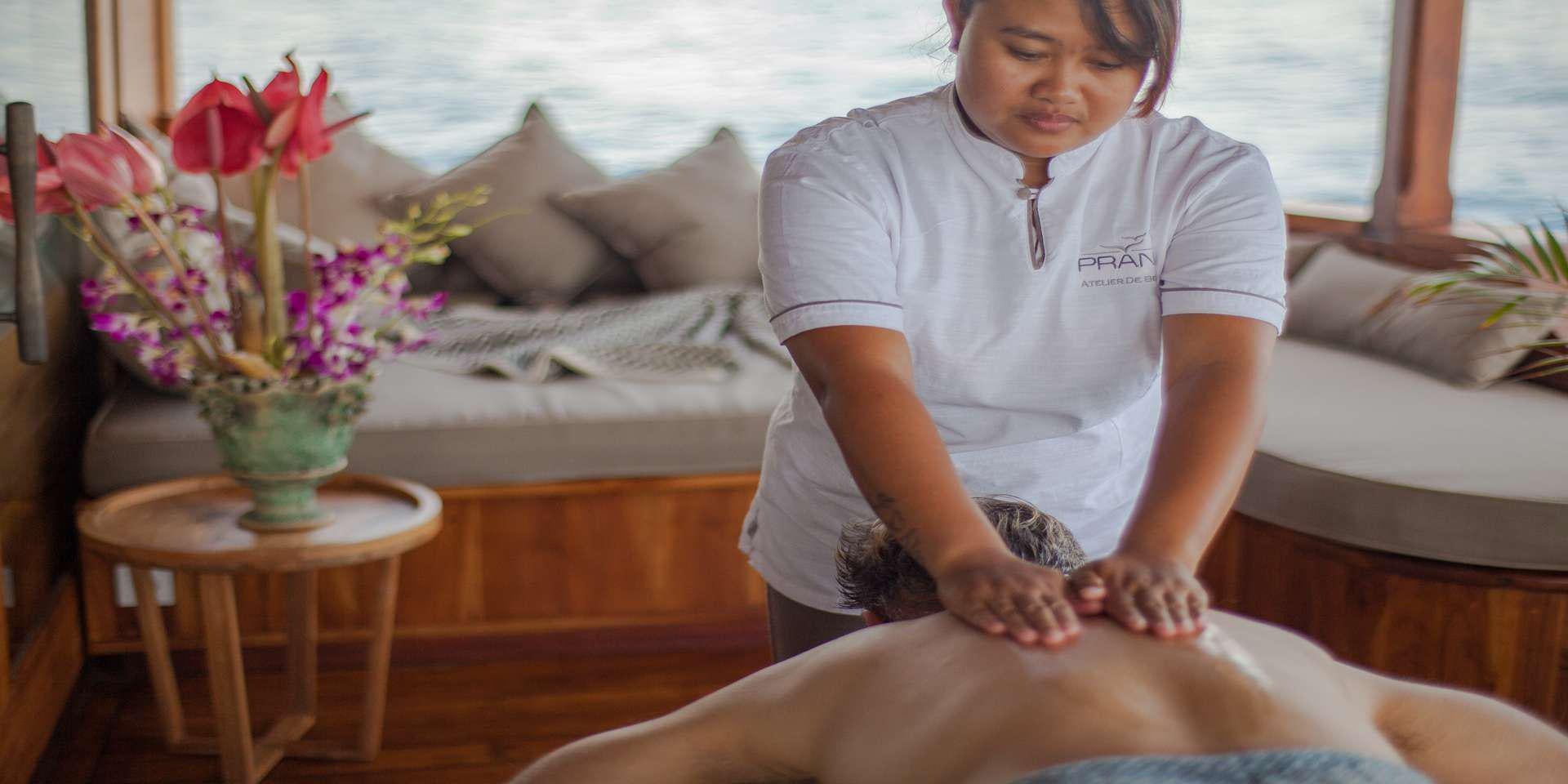 a person sitting on a couch with a vase of flowers aboard PRANA Yacht for Charter
