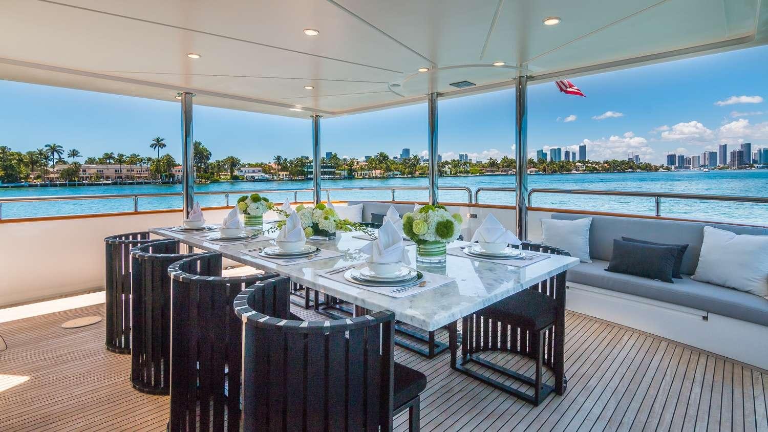a table with chairs and a view of a city aboard NIRVANA Yacht for Charter