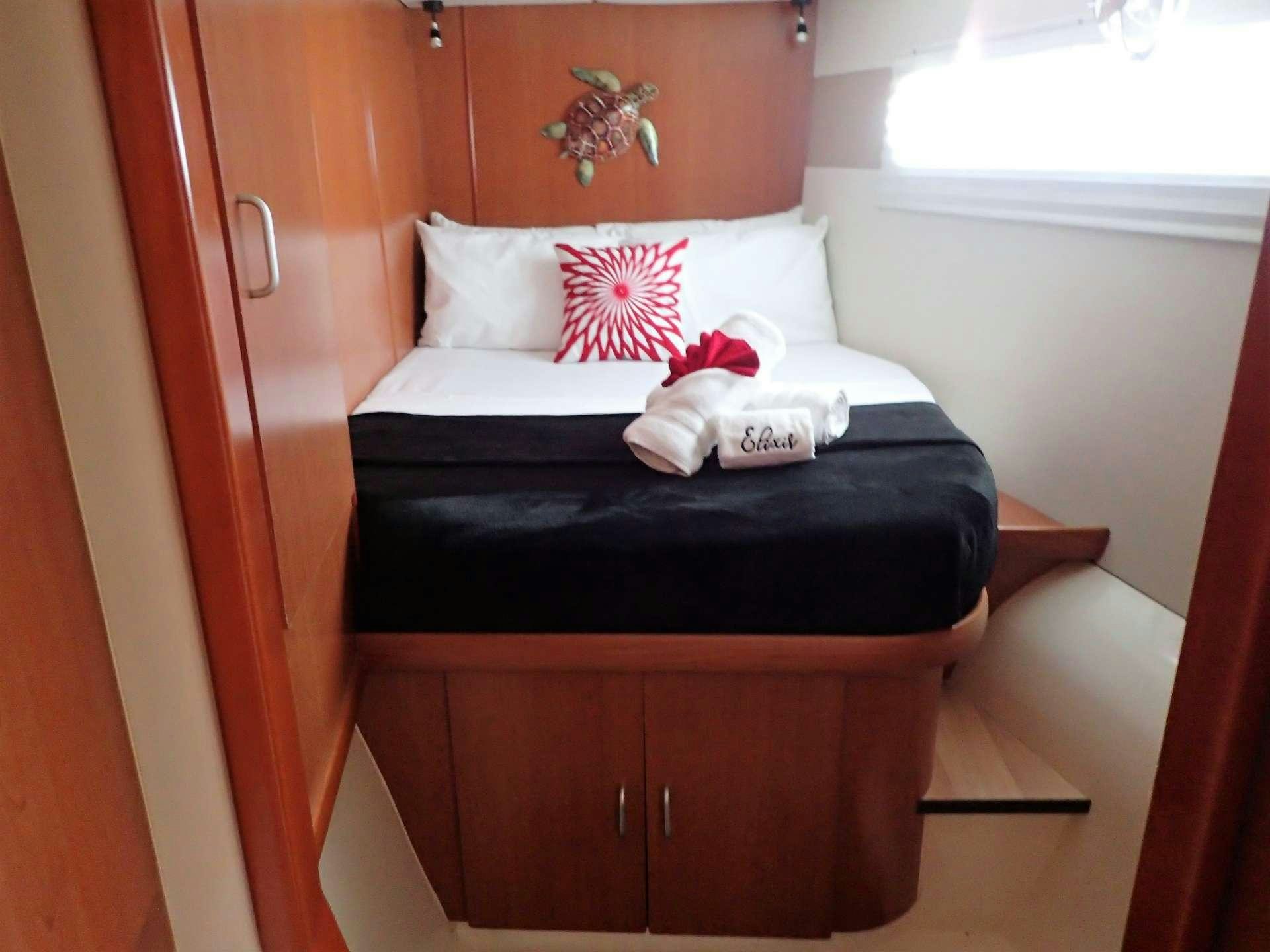 a bed with a black pillow and red and white pillows on it aboard ELIXIR Yacht for Charter